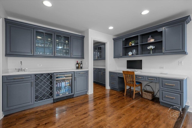 office area featuring beverage cooler, dark wood finished floors, indoor wet bar, built in desk, and recessed lighting