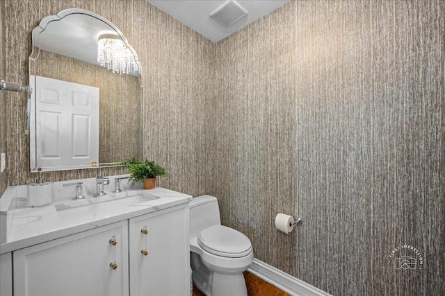 bathroom with visible vents, toilet, wallpapered walls, baseboards, and vanity