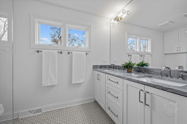 bathroom with double vanity, baseboards, visible vents, and a sink