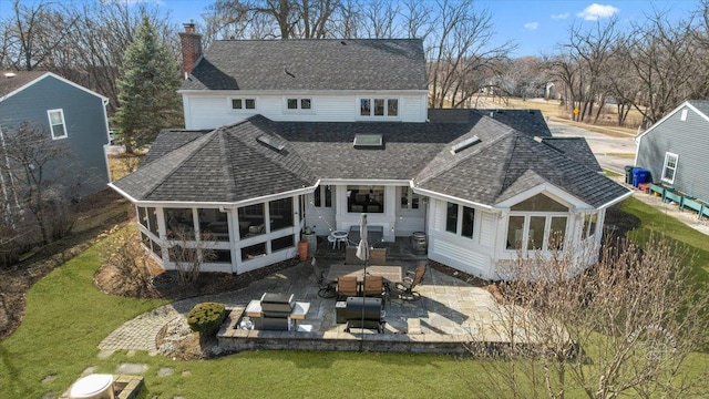 rear view of property featuring a patio area, a yard, roof with shingles, and a sunroom