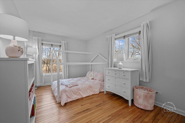 bedroom with multiple windows, baseboards, and light wood-type flooring