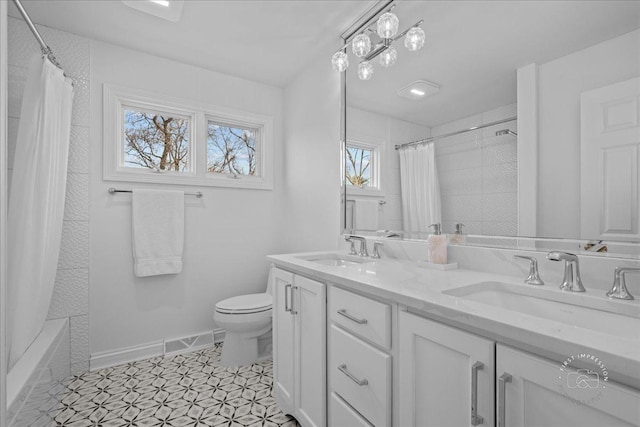 full bath with a sink, baseboards, toilet, and double vanity