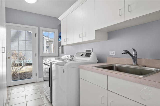 laundry area featuring a sink, cabinet space, light tile patterned floors, and washer and clothes dryer