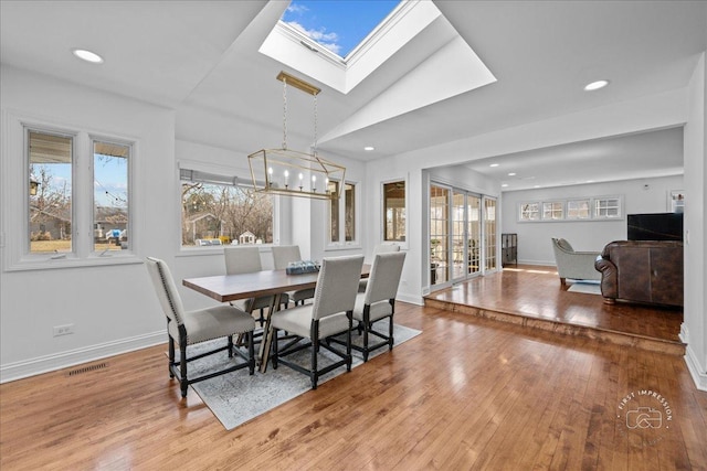 dining room featuring plenty of natural light, baseboards, visible vents, and wood-type flooring