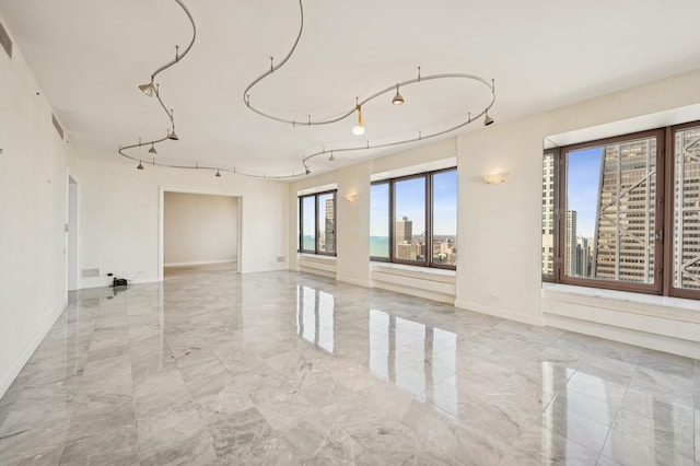 unfurnished room featuring baseboards, a view of city, marble finish floor, and track lighting