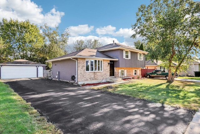 tri-level home with an outbuilding, brick siding, a detached garage, and a front lawn