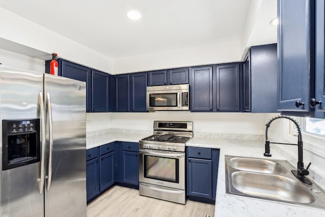 kitchen with blue cabinetry, recessed lighting, light wood-style flooring, appliances with stainless steel finishes, and a sink