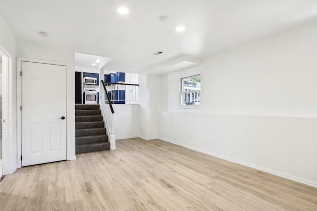 spare room with recessed lighting, light wood-type flooring, baseboards, and stairs