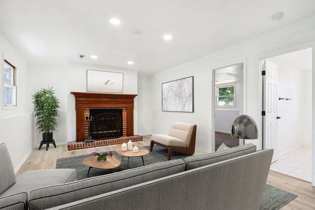 living area with recessed lighting, a brick fireplace, baseboards, and wood finished floors