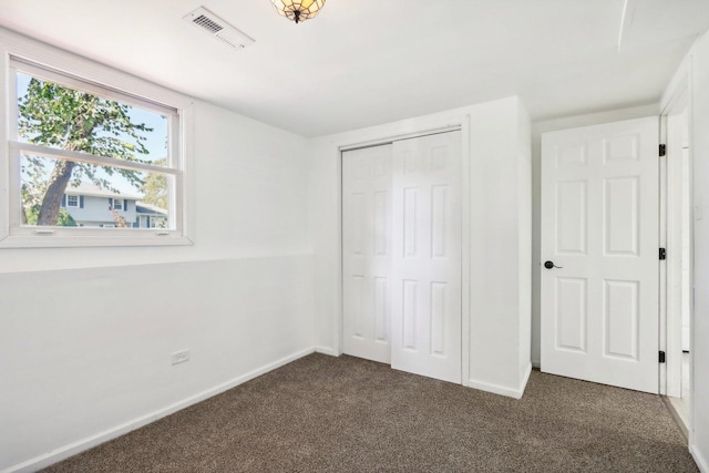 unfurnished bedroom featuring a closet, visible vents, baseboards, and dark colored carpet