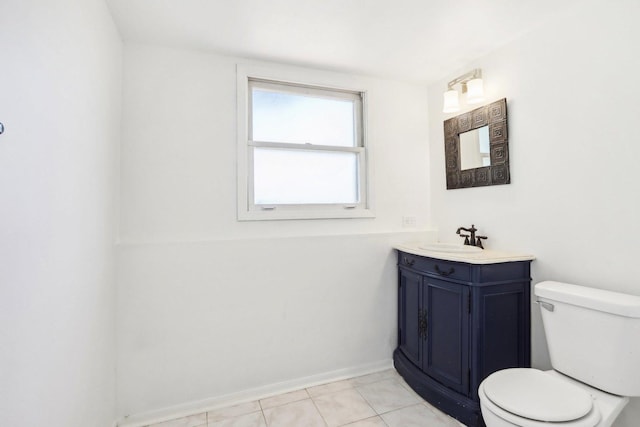 half bath with tile patterned floors, baseboards, toilet, and vanity