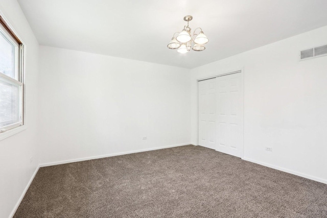 spare room with a notable chandelier, visible vents, baseboards, and carpet floors