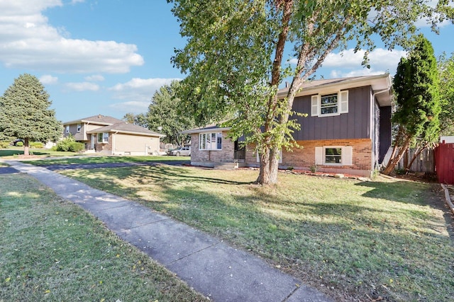 split level home with a front yard, fence, and brick siding