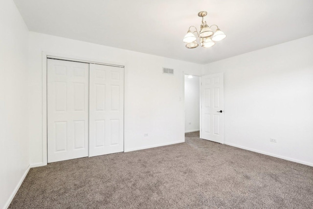 unfurnished bedroom with visible vents, baseboards, carpet flooring, an inviting chandelier, and a closet