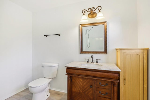 bathroom featuring toilet, vanity, and baseboards