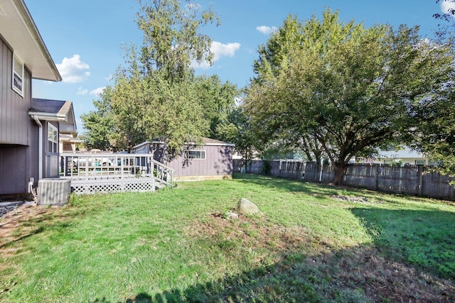 view of yard featuring an outbuilding, central AC, a deck, and fence