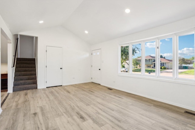 interior space with visible vents, light wood-style flooring, stairway, baseboards, and vaulted ceiling