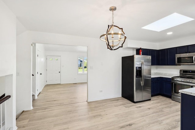 kitchen featuring pendant lighting, light countertops, light wood-style flooring, appliances with stainless steel finishes, and a skylight