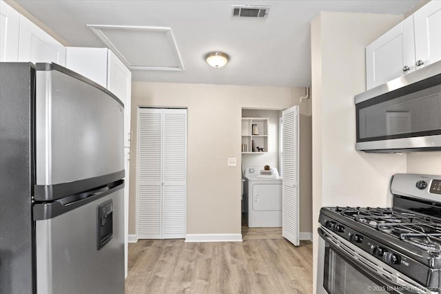 kitchen featuring light wood-type flooring, visible vents, white cabinetry, stainless steel appliances, and washer / dryer