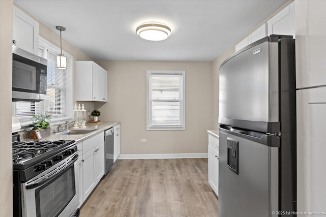 kitchen featuring a sink, white cabinets, light wood-style floors, and stainless steel appliances