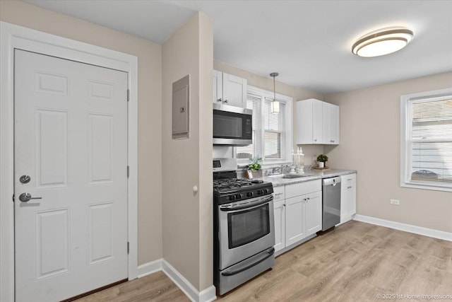 kitchen with a wealth of natural light, white cabinets, appliances with stainless steel finishes, and a sink