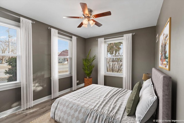 bedroom with a ceiling fan, baseboards, and wood finished floors