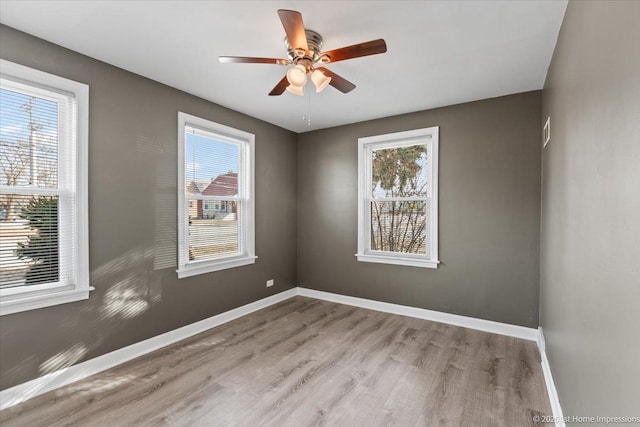 unfurnished room featuring plenty of natural light, baseboards, and wood finished floors