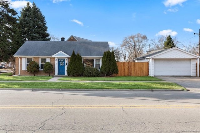 view of front of house with a detached garage, fence, a front yard, brick siding, and a chimney