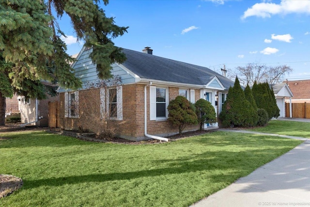 view of front of house with brick siding, a chimney, a front yard, and a shingled roof