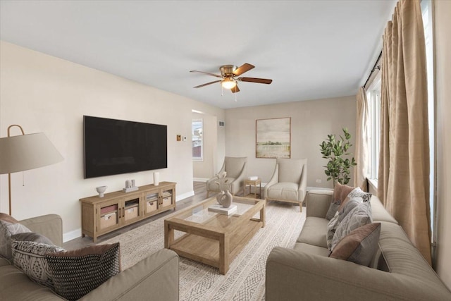 living room with baseboards, wood finished floors, and a ceiling fan