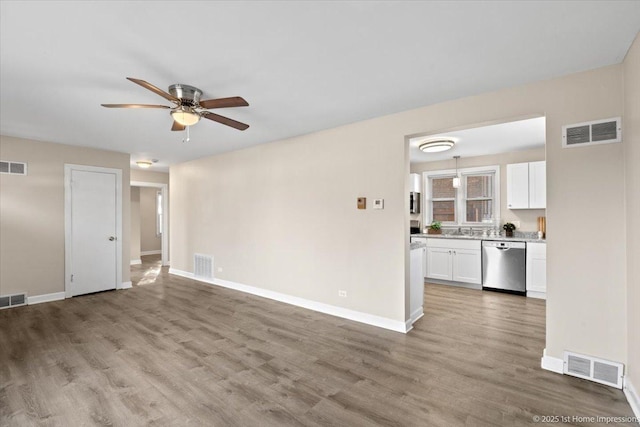 unfurnished living room featuring wood finished floors, baseboards, and visible vents