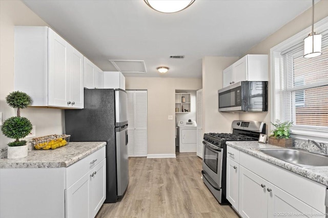 kitchen featuring visible vents, a sink, appliances with stainless steel finishes, white cabinets, and washer / dryer