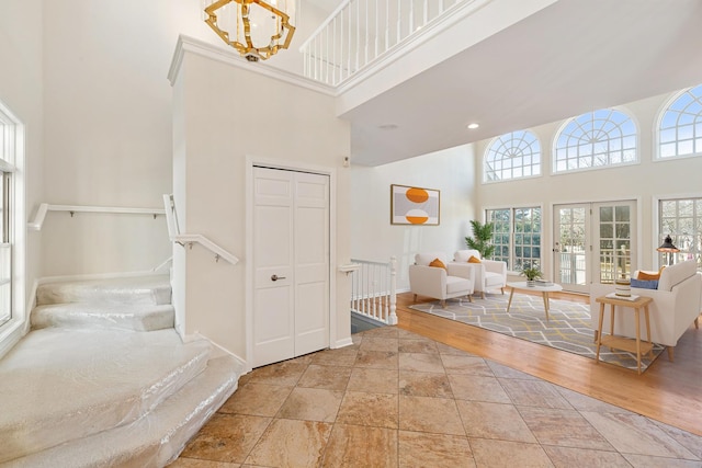 entrance foyer with wood finished floors, baseboards, a high ceiling, stairs, and a notable chandelier