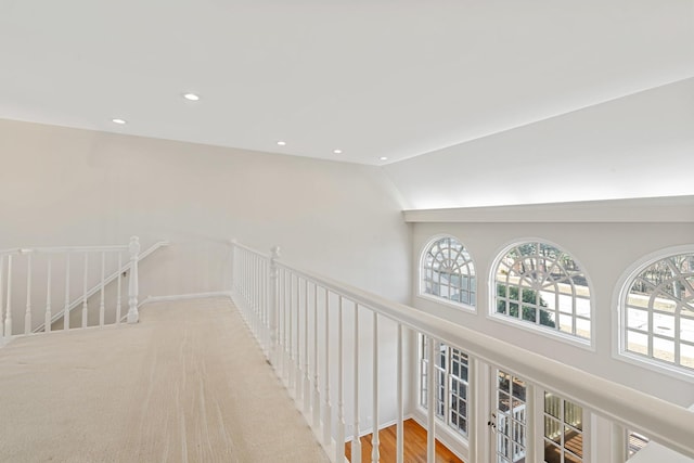 corridor featuring lofted ceiling, plenty of natural light, recessed lighting, and an upstairs landing