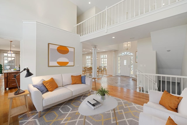 living room featuring a notable chandelier, plenty of natural light, wood finished floors, and a towering ceiling