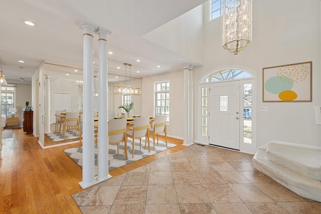 foyer entrance featuring a chandelier, plenty of natural light, recessed lighting, and ornate columns