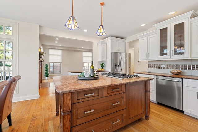 kitchen featuring a wealth of natural light, stainless steel appliances, light wood-style flooring, and white cabinetry