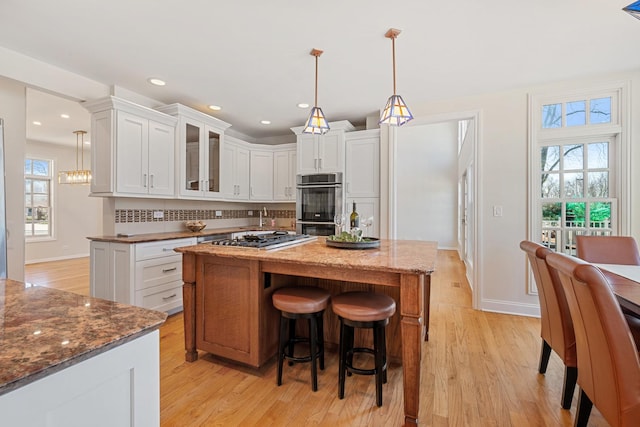 kitchen with tasteful backsplash, white cabinets, and light wood-style floors