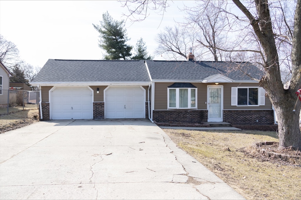 ranch-style house featuring an attached garage, brick siding, driveway, and a chimney