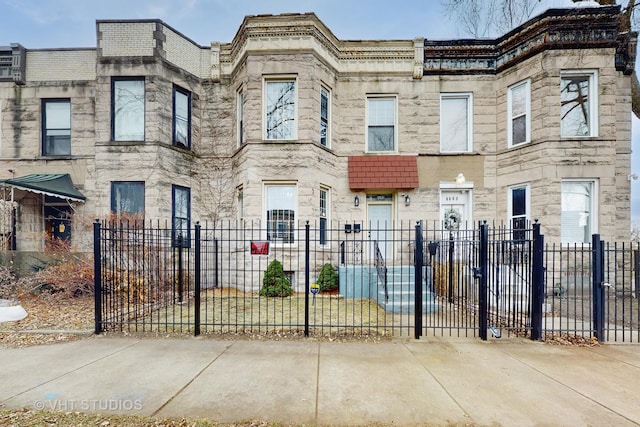 townhome / multi-family property with stone siding and a fenced front yard