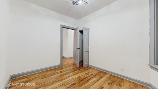 spare room featuring baseboards and light wood-style floors