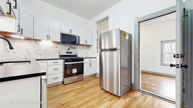 kitchen with a sink, tasteful backsplash, appliances with stainless steel finishes, and white cabinetry