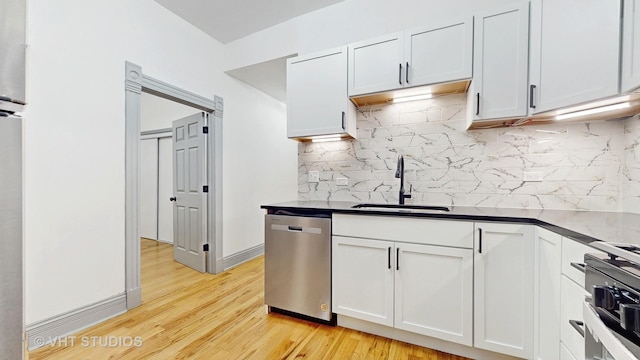 kitchen with a sink, tasteful backsplash, dishwasher, and light wood finished floors