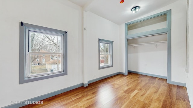 unfurnished bedroom with a closet, light wood-style flooring, and baseboards