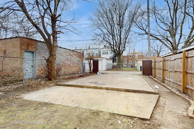 view of yard featuring fence private yard, an outdoor structure, a storage unit, a patio, and a gate