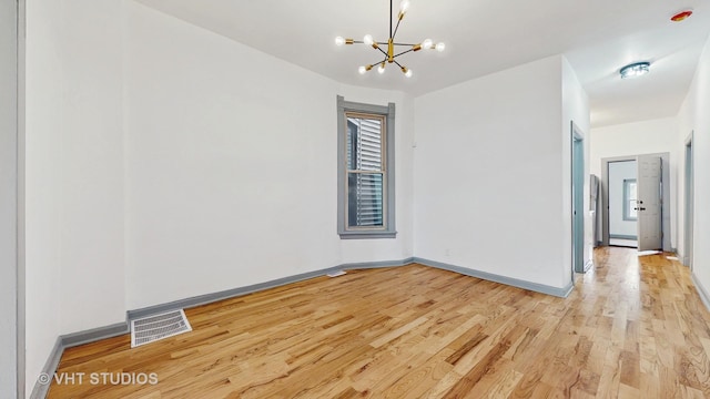 unfurnished room with light wood-style flooring, baseboards, visible vents, and a chandelier