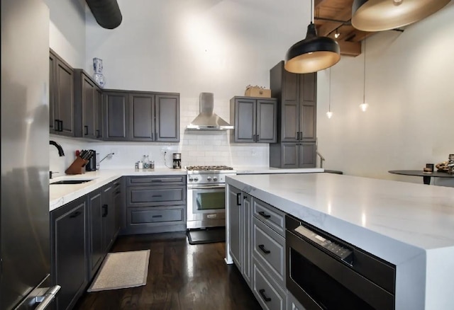 kitchen featuring backsplash, gray cabinetry, dark wood-type flooring, stainless steel appliances, and wall chimney exhaust hood