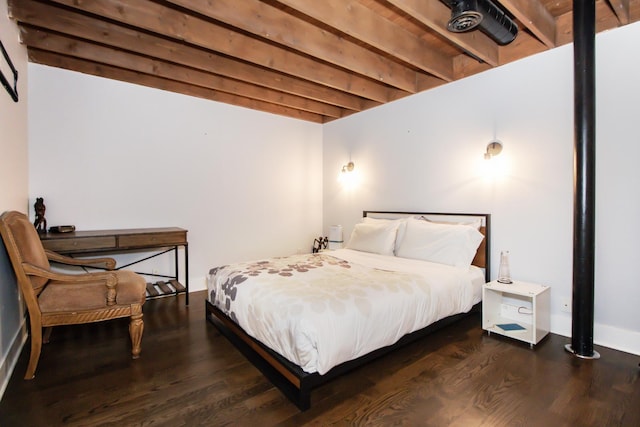 bedroom with beam ceiling and wood finished floors