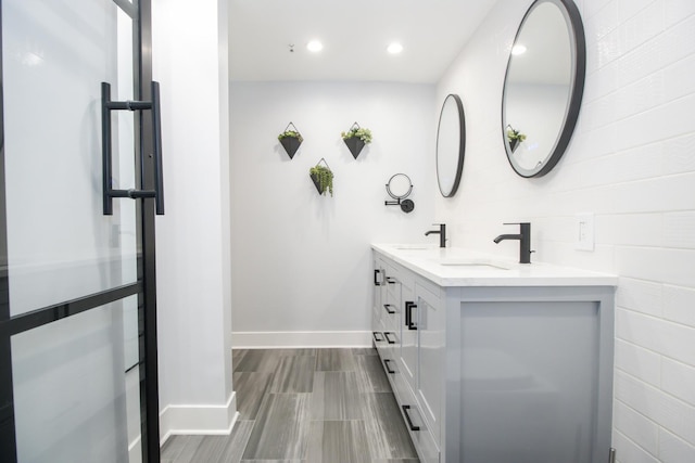 bathroom featuring double vanity, recessed lighting, baseboards, and a sink