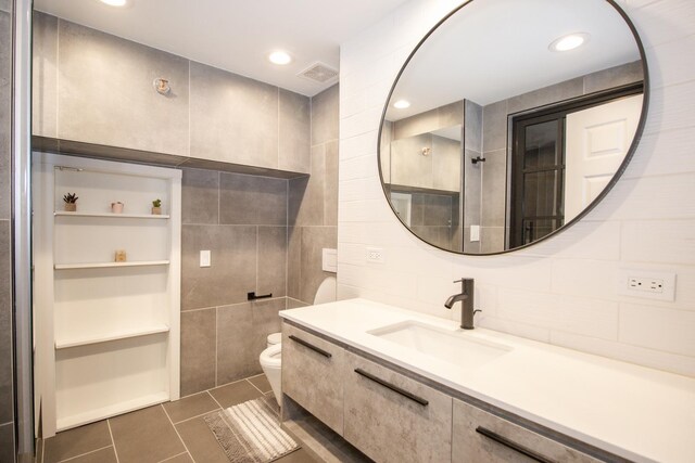 bathroom featuring tile patterned floors, visible vents, toilet, tile walls, and vanity